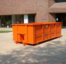 An orange dumpster in front of an office building.