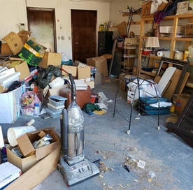 A room filled with junk including a vacuum and boxes.